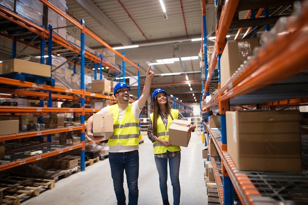 Workers carrying boxes and relocating packages to appropriate position on the shelf for good organization at storage center