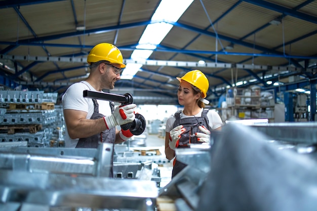 Free photo workers checking quality of metal parts manufactured in factory