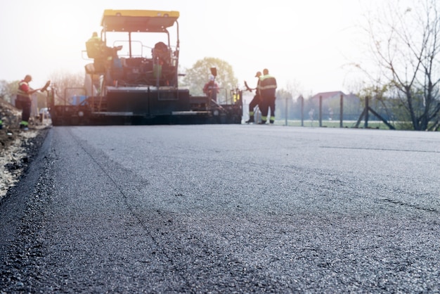 Free Photo workers placing new coating of asphalt on the road