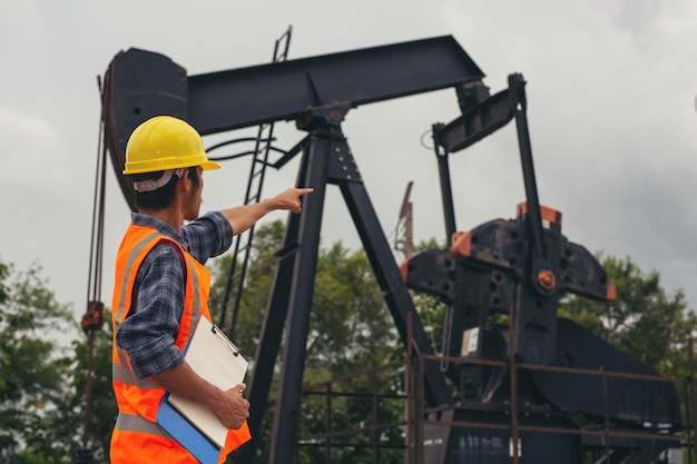 Workers standing and checking beside working oil pumps.