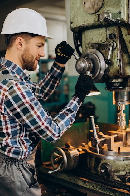 Free photo workman wearing hard hat working with metal constructions at factory