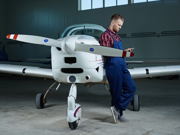 Free Photo workman with smartphone and a plane