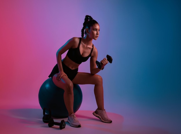 Workout young asian woman doing weightlifting exercise with dumbbell in fitness