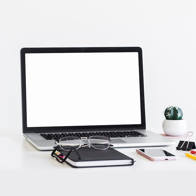 Workplace with laptop near eyeglasses, notepad and mobile phone