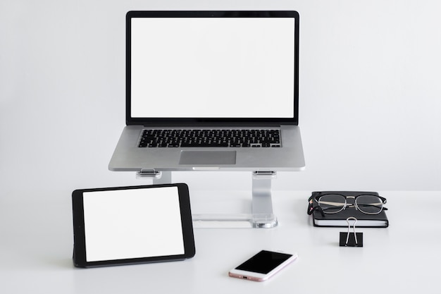 Free Photo workplace with laptop on stand near eyeglasses, tablet and smartphone