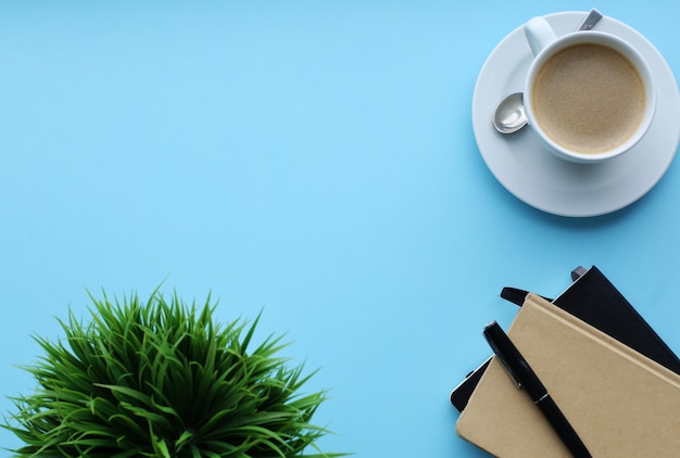 Workplace with plant, notebooks and coffee cup