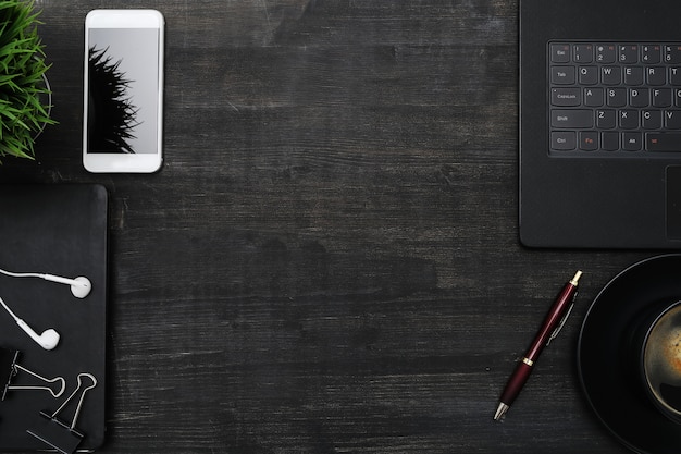 Workplace with smartphone, laptop, on black table. Top view copyspace background