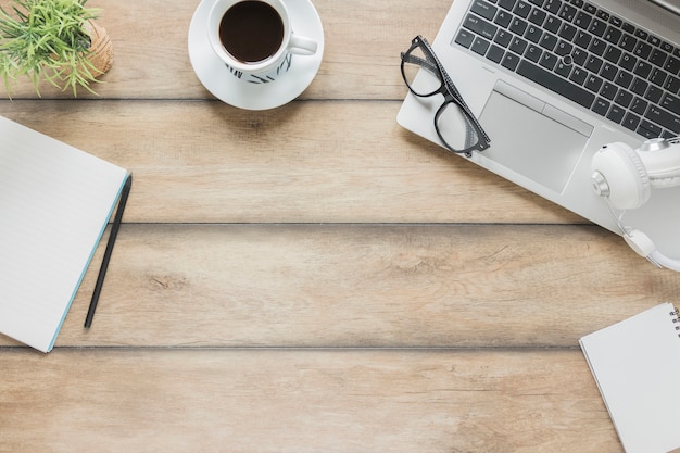 Workplace with stationery, electronic devices and coffee cup on wooden table