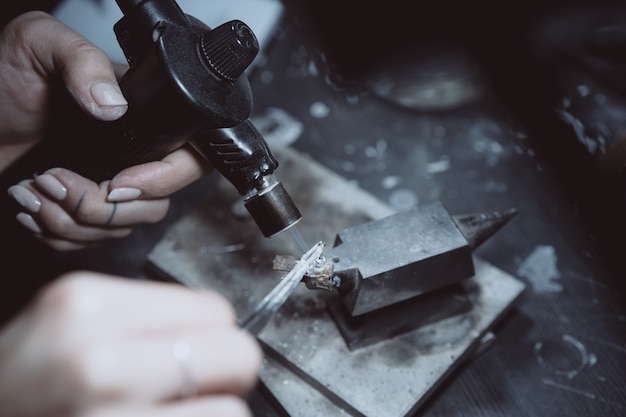 Free photo in the workshop, a woman jeweler is busy soldering jewelry