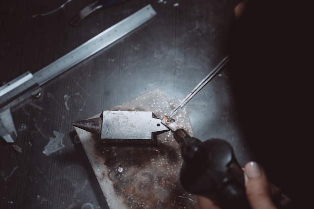 In the workshop, a woman jeweler is busy soldering jewelry