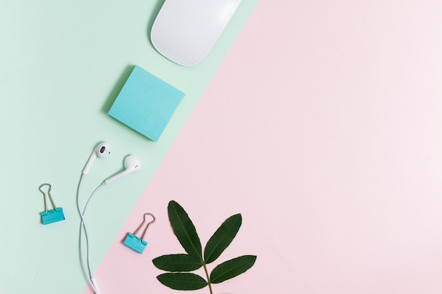 Free Photo workspace with earphones and mouse on pink and green background 