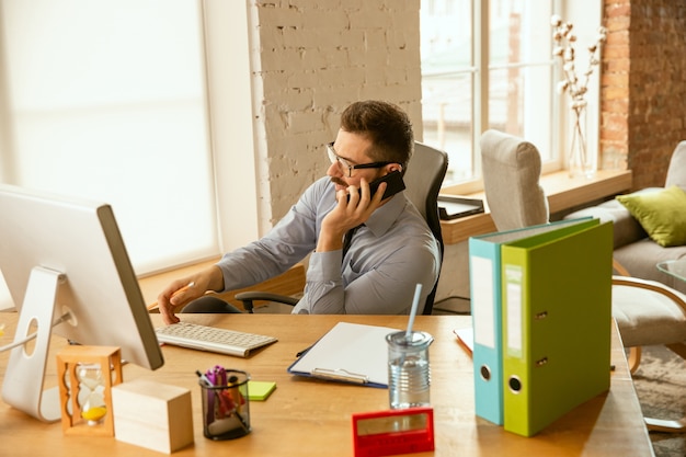 Free photo worktime. a young businessman moving in the office, getting new work place. young male office worker while managing after promotion. looks happy