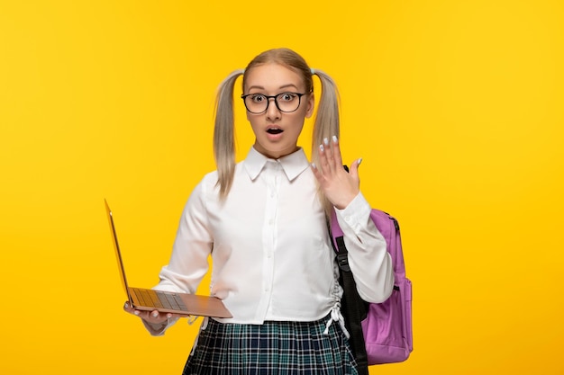 World book day surprised blonde student with waving hands holding a computer