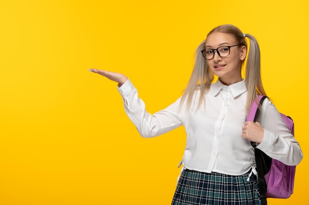 World book day young blonde schoolgirl with waving hands in uniform