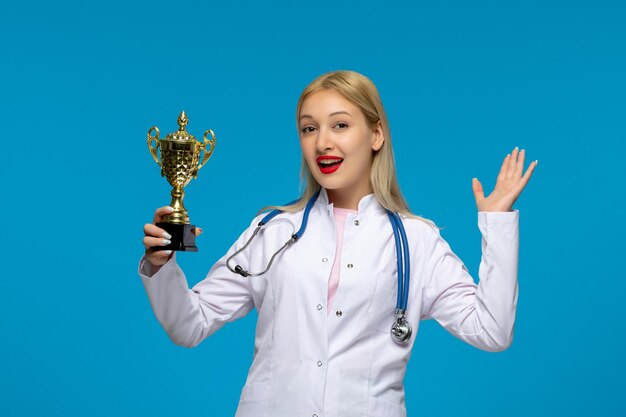 World doctors day smiling cute doctor with golden trophy and the stethoscope in the lab coat