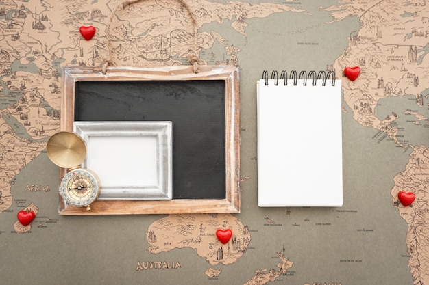 Free Photo world map background with blank notebook and travel items