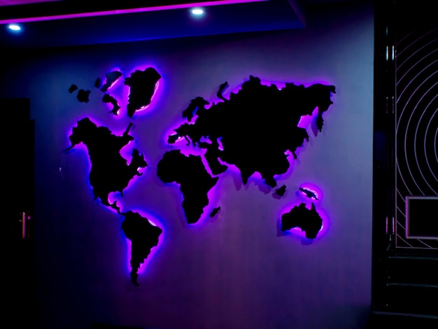 Free photo world map installed on the wall with purple neon lights in the dark room