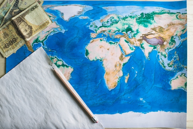 Free photo world map with piece of paper and banknotes