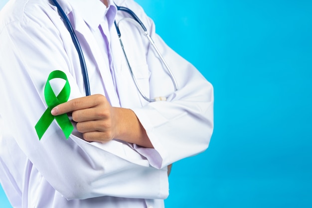 Free photo world mental health day. doctor's hand holding green ribbon