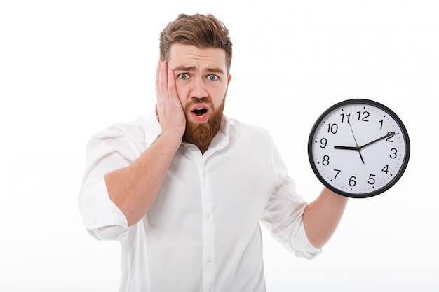 Worried bearded man in business clothes holding clock