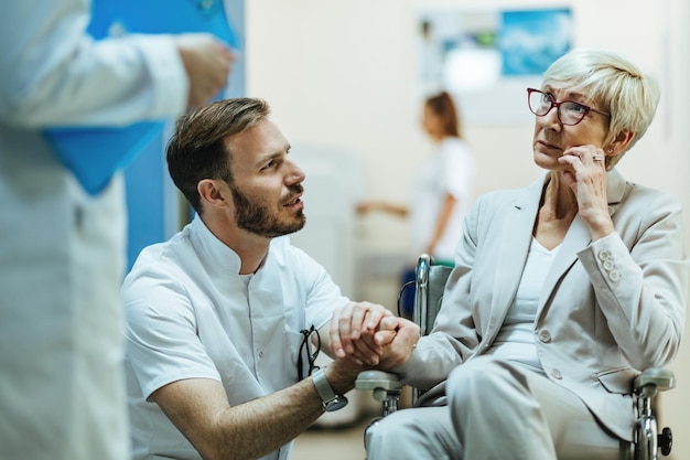 Free Photo worried mature woman in wheelchair communicating with doctors at medical clinic