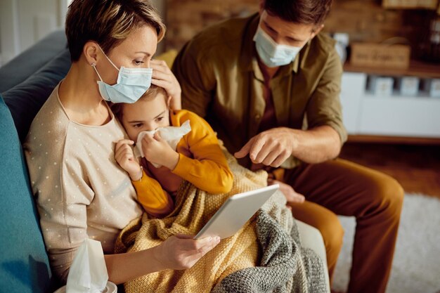 Worried parents with face masks talking via video call with a doctor about their ill daughter