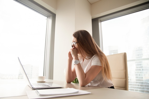 Worried thoughtful businesswoman thinking hard of problem, looking at laptop