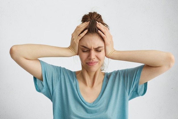 Free photo worried woman closing her eyes with hands on head having headache