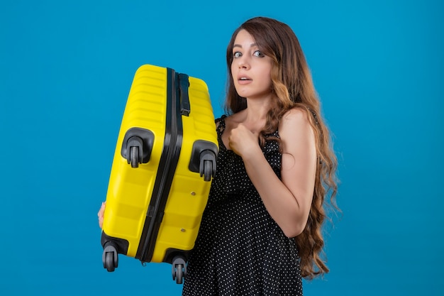 Free Photo worried young beautiful traveler girl holding suitcase nervous and very anxious looking at camera standing over blue background