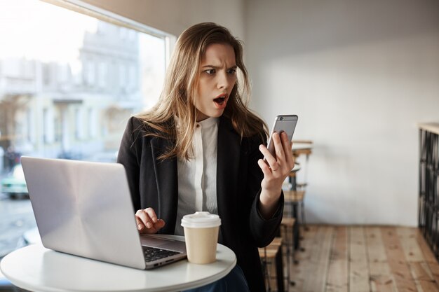 Worried young businesswoman at cafe looking the smartphone