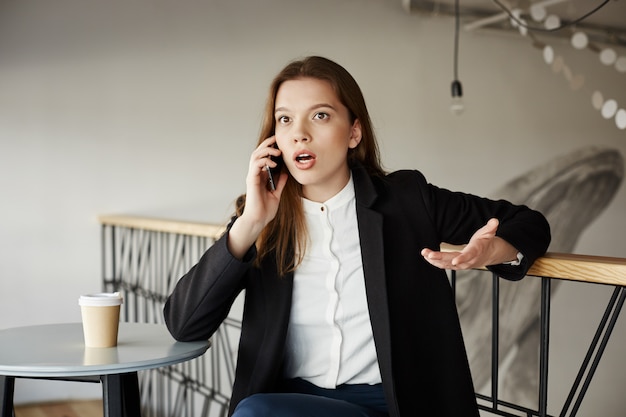 Free Photo worried young businesswoman at cafe talking by phone