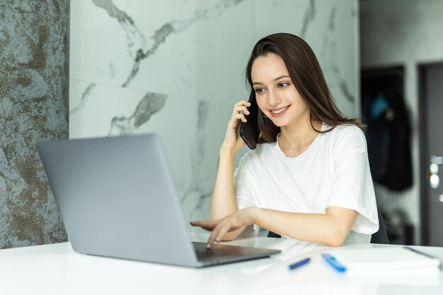 Worried young dressed casually sitting at kitchen table, holding paper sheet and talking to house and utilities service representative about miscalculation in bills