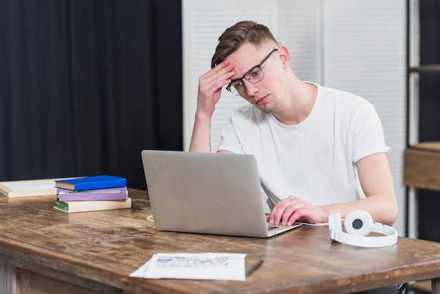 Worried young man looking at laptop on wooden table