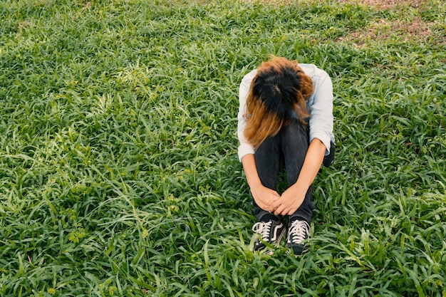 Free photo worried young woman sitting on the grass