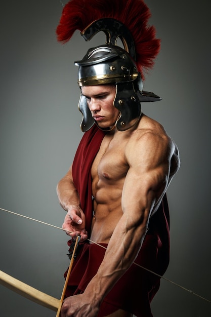 Free photo wounded gladiator with bow isolated on grey.