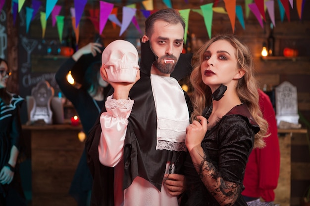 Free Photo wounderful couple in halloween costumes at a party. man dressed up like dracula for halloween celebration.