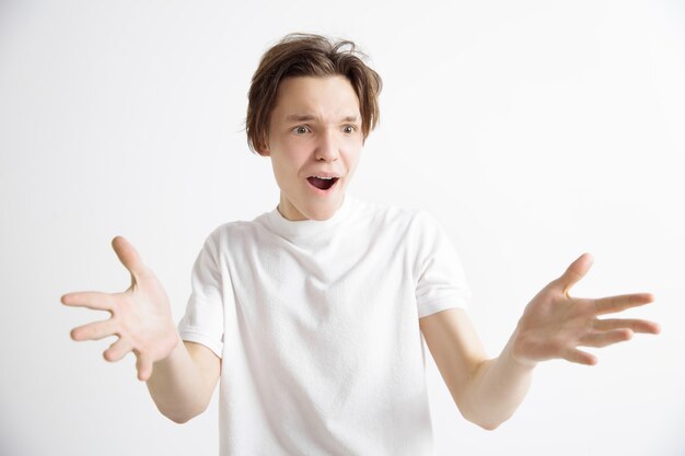 Wow. Attractive male half-length front portrait on gray studio backgroud. Young emotional surprised man standing with open mouth. Human emotions, facial expression concept