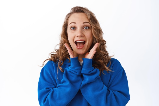 Free Photo wow omg. impressed blond girl look with excitement, staring amazed and gasping at camera, checking out fascinating awesome thing, standing over white background