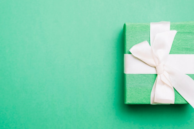 Wrapped birthday present with white ribbon bow on green background