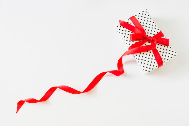 Free photo wrapped gift tied with red ribbon on white backdrop