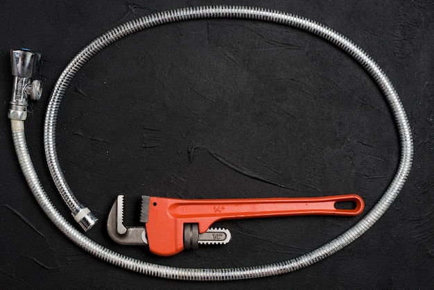 Free Photo wrench and flexible connector on dark table