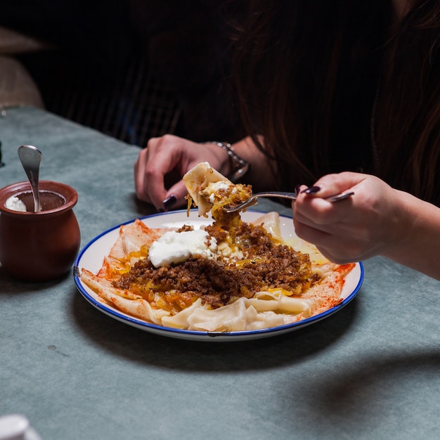 xengel with yogurt and human hand and fork in round plate