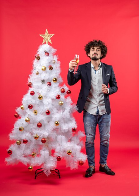 xmas celebration with bearded proud young man with wine standing near Christmas tree