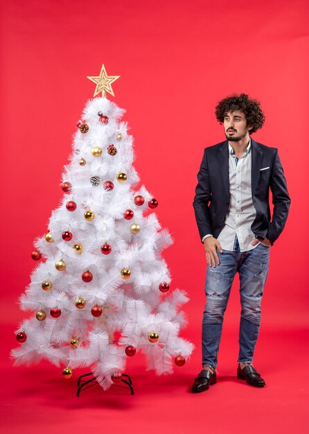 xmas celebration with bearded young man looking at something standing near Christmas tree