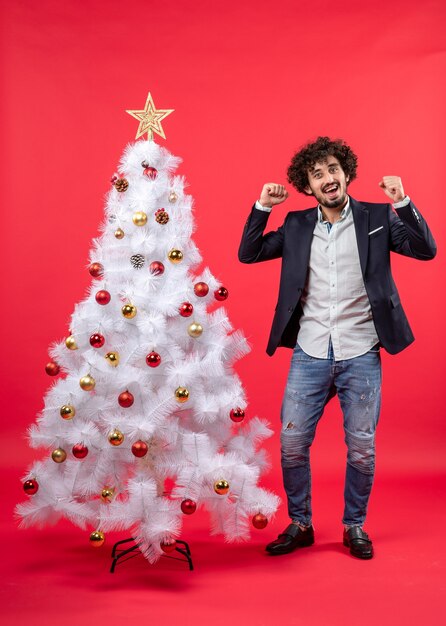 xmas celebration with happy excited young man proud of himself and standing near Christmas tree