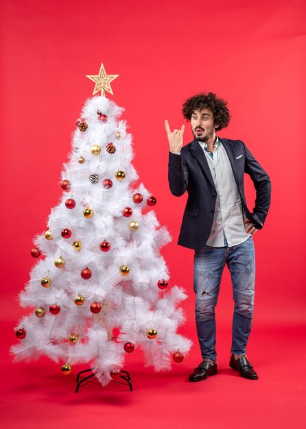 xmas celebration with happy funny excited young man making victory gesture and standing near Christmas tree