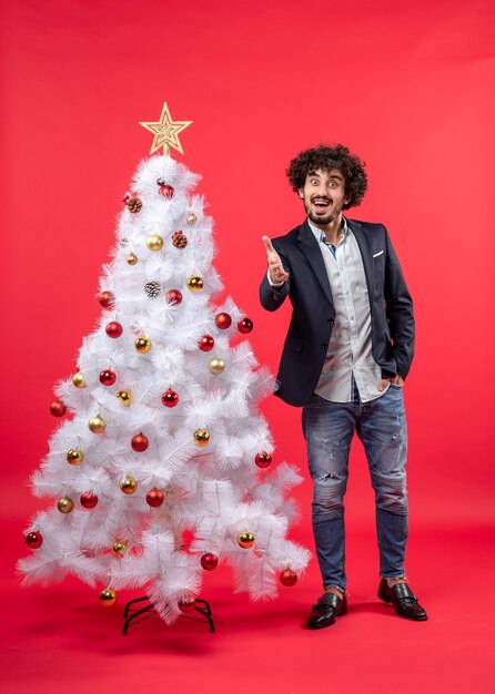 xmas celebration with happy funny young man welcoming someone standing near Christmas tree