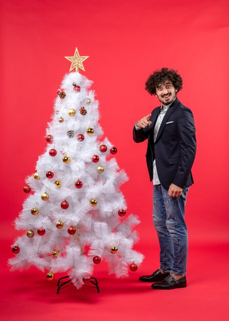 xmas celebration with young happy excited funny man pointing something standing near Christmas tree