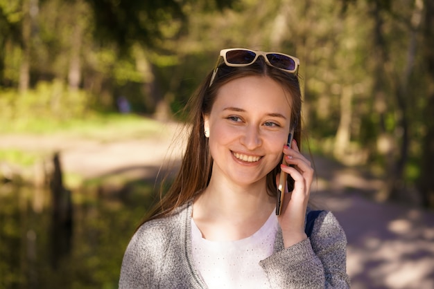 Y a young beautiful girl with sunglasses walks and talks on the phone on a sunny spring day