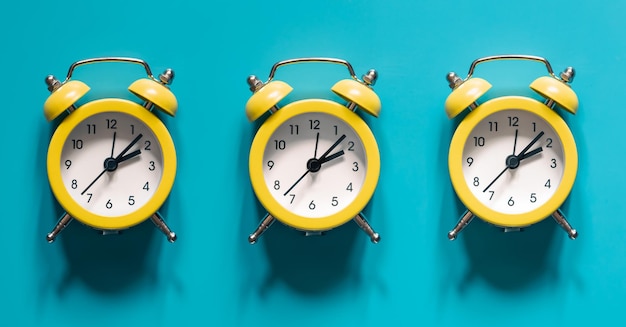 Yellow alarm clocks on blue background isolated flat lay